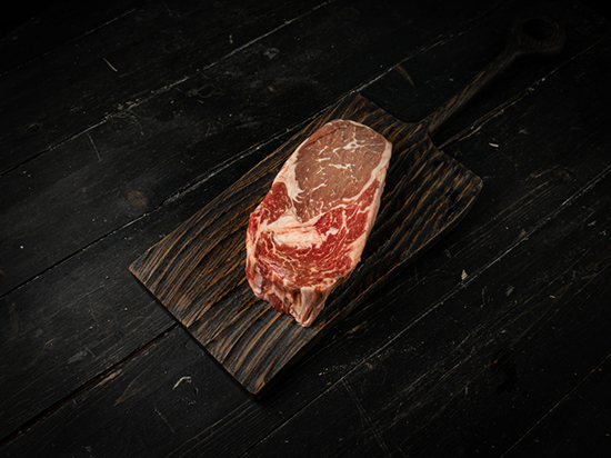 A bright red cut of raw beef with a section that has a brown color.